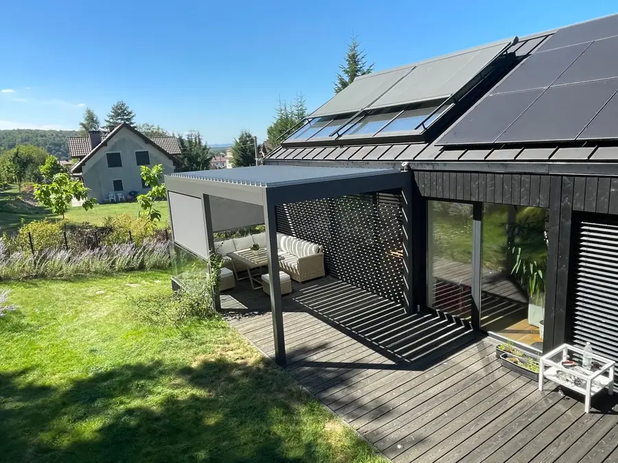 Antracytowa pergola z dachem lamelowym i boczną osłoną screen nad drewnianym tarasem